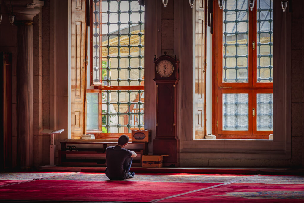 In a mosque man sitting on a carpet in a mosque